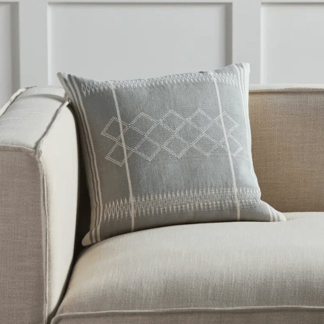 Nagaland Sanis throw pillow with a handcrafted tribal pattern in light gray and cream, perfect for sofas, chairs, or beds, adding texture and cultural charm to any space.