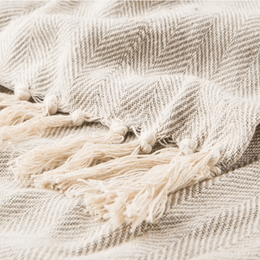 Seabreeze handcrafted cotton throw blanket in herringbone stripe pattern; soft, breathable textile ideal for layering on sofas, chairs, or beds, adding coastal-inspired style to home décor.  Beige